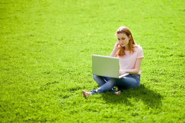 Girl with a laptop sitting on the lawn