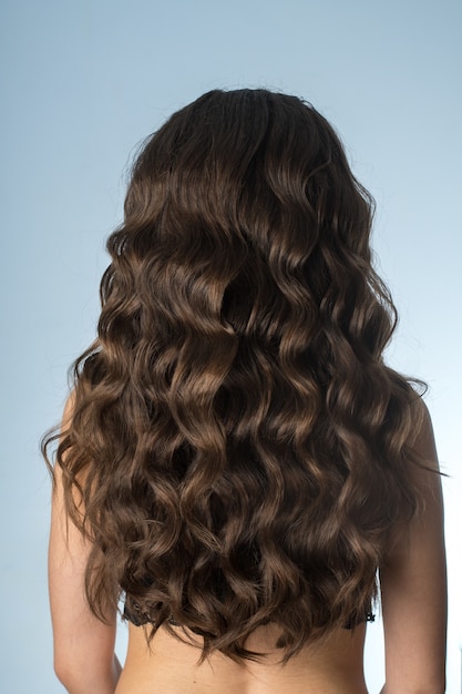 Girl with long curly hair in studio on grey