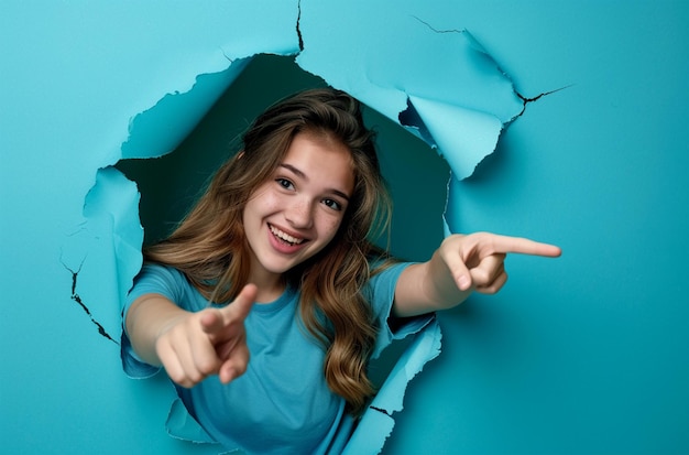 Photo a girl with long hair and a blue shirt pointing at a blue paper