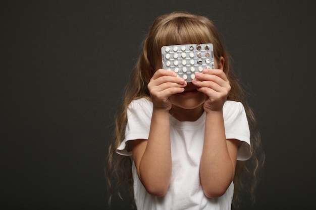 Photo girl with long hair holds pills and hides her face.