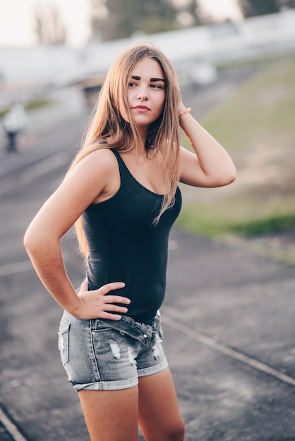 Girl with long hair posing on street at sunset girl with beautiful skin color looks to the side