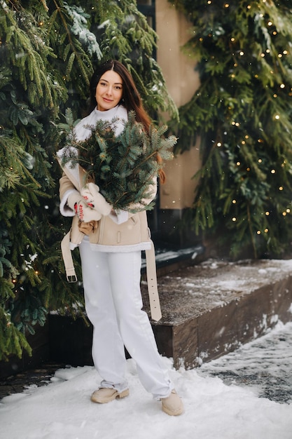 A girl with long hair in winter on the street with a bouquet of fresh fir branches