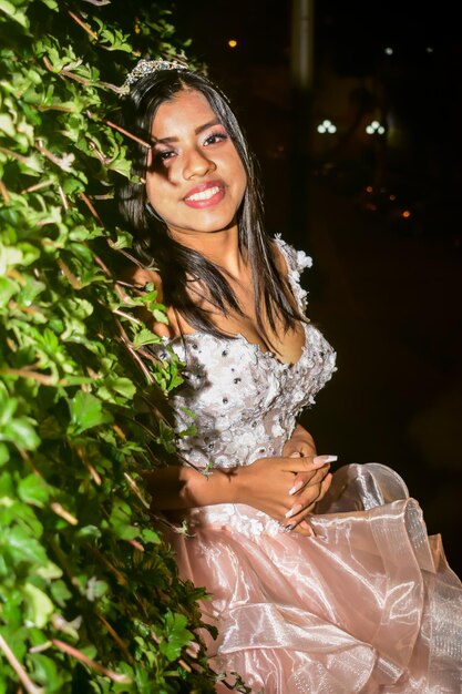 Girl with makeup and hairstyle in a princess dress, near plants in a garden.