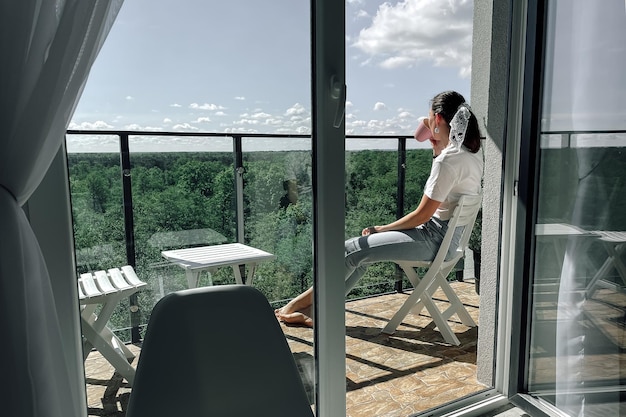 A girl with a mug on the balcony drinks morning tea and takes a break from the hustle and bustle of the city Lifestyle morning tea party