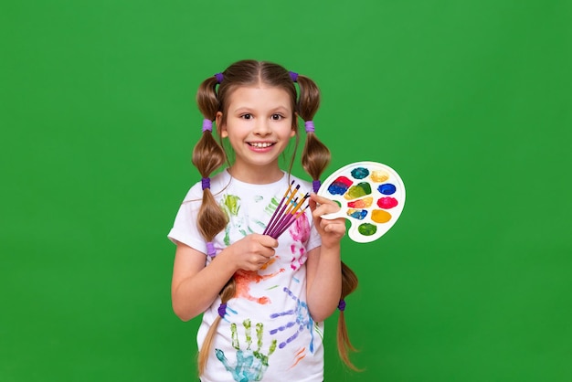 A girl with paints on a green isolated background children's creativity courses in painting with watercolors and gouache