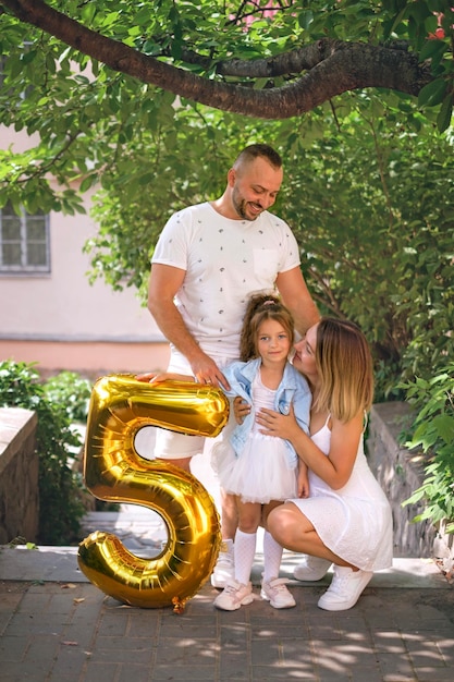 Girl with parents and figure balloon in the shape of five