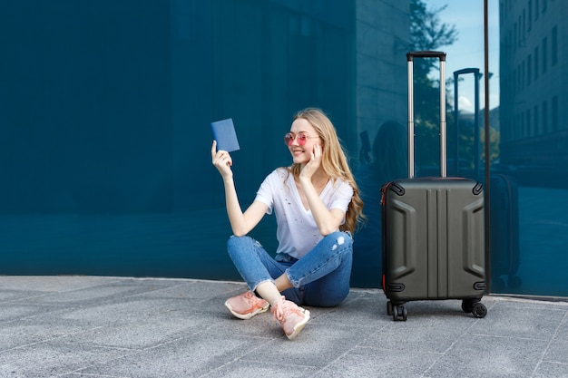 Girl with passport, luggage, and glasses near the window