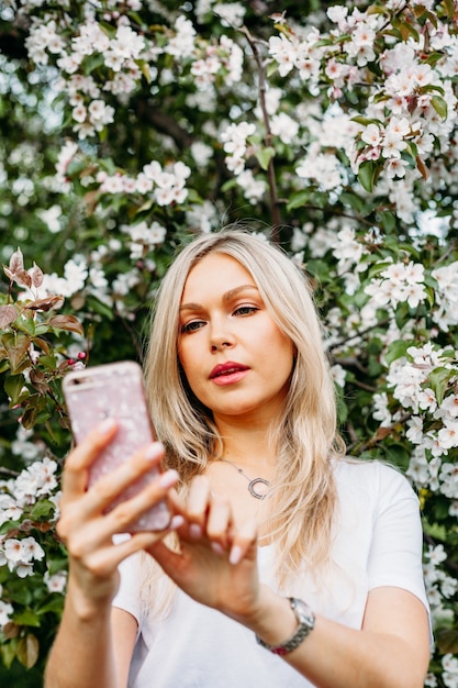 A girl with a phone in her hand takes pictures of herself, selfies