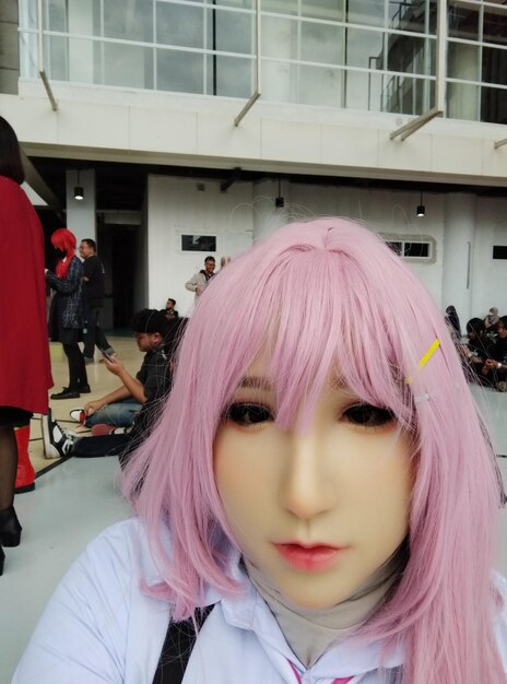 Photo a girl with pink hair and a pink wig stands in front of a building