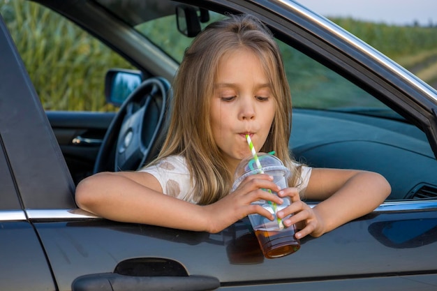 A girl with a plastic glass of a cocktail in a car