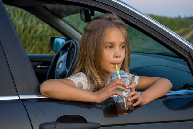 A girl with a plastic glass of a cocktail in a car