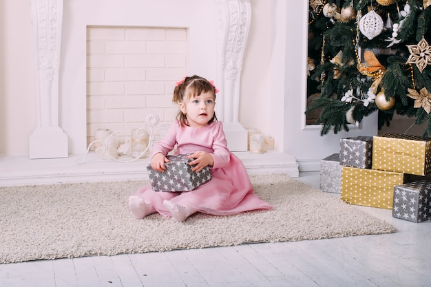 Girl with presents and Christmas tree on the background 