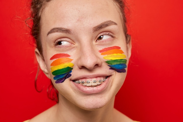 Girl with pride flag painted on her cheeks smiling