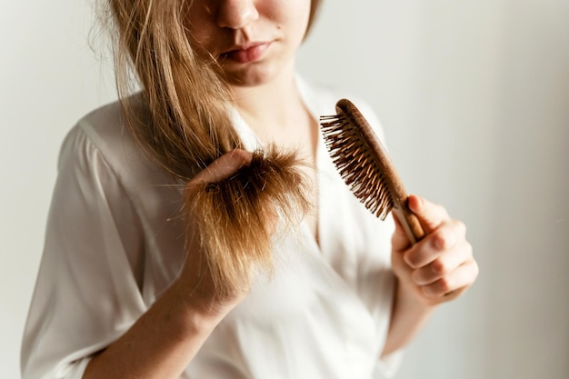 Photo a girl with problematic hair sits on the bed and combs them girl with a comb sits on a bed in pajamas