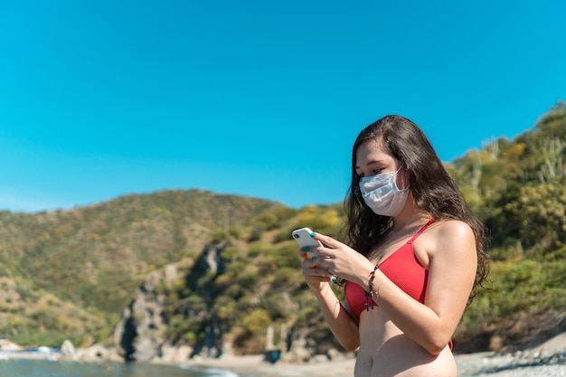 Girl with protective mask and telephone in bathing suit