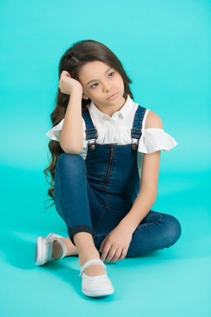 Girl with serious face long brunette hair on blue background