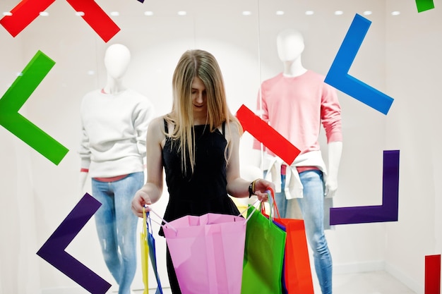 Girl with shopping bags in the mall against mannequins in the showwindow