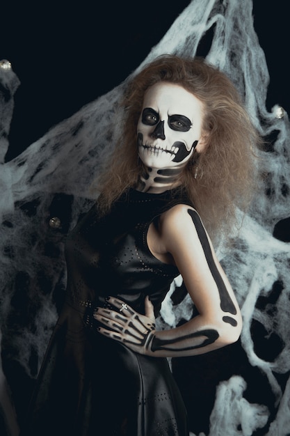 Girl with skeleton makeup posing in webs