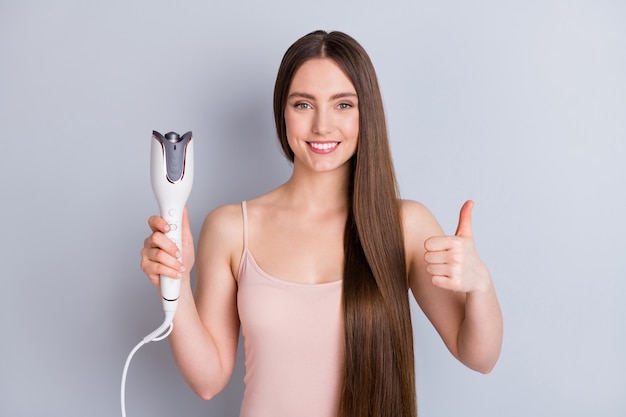 girl with straightener device in hand isolated on gray