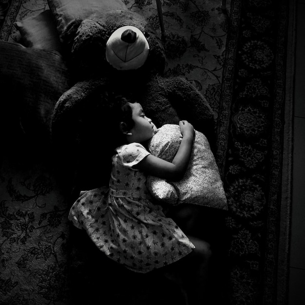 Photo girl with toys sleeping on bed in darkroom