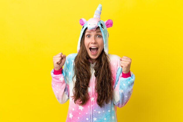 Girl with unicorn pajamas over isolated background celebrating a victory in winner position