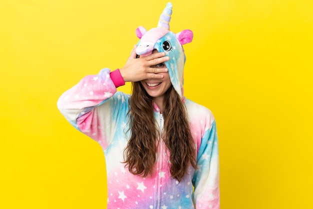 Girl with unicorn pajamas over isolated background covering eyes by hands and smiling