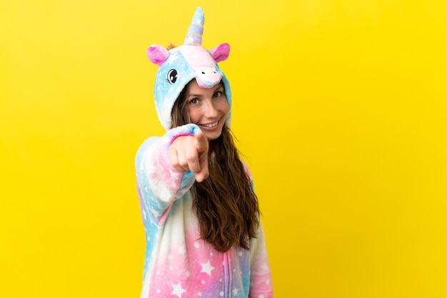 Girl with unicorn pajamas over isolated background points finger at you with a confident expression