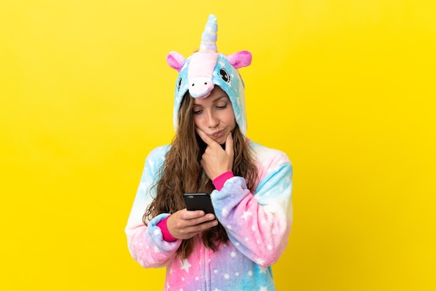 Girl with unicorn pajamas over isolated background thinking and sending a message