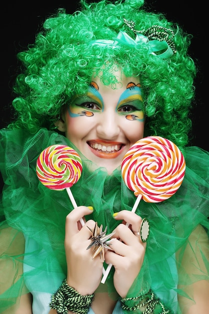 Girl with with creative make-up holds lollipop. Doll style.