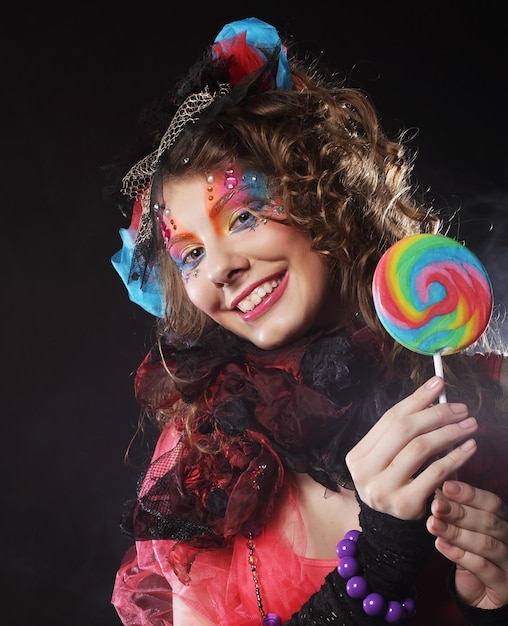 Girl with with creative makeup holds lollipop Doll style