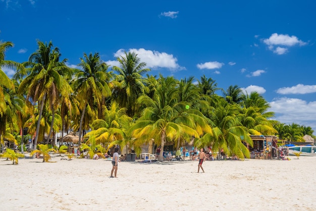 Girl woman and boy are playing with a ball on a white sand beach with cocos palms Isla Mujeres island Caribbean Sea Cancun Yucatan Mexico