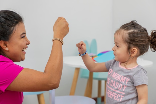 A girl and a woman bumping their fists after finishing their activities in preschool