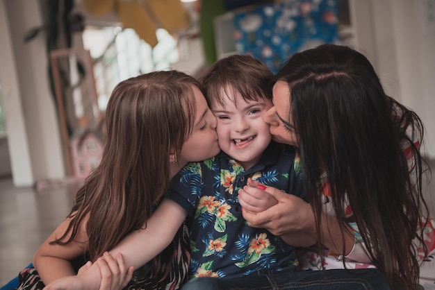 A girl and a woman hug a child with down syndrome in a modern preschool institution