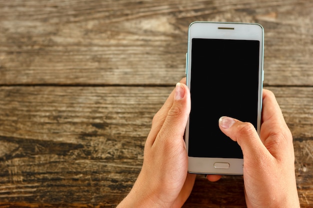 Girl at a wooden table holding a phone in her hand