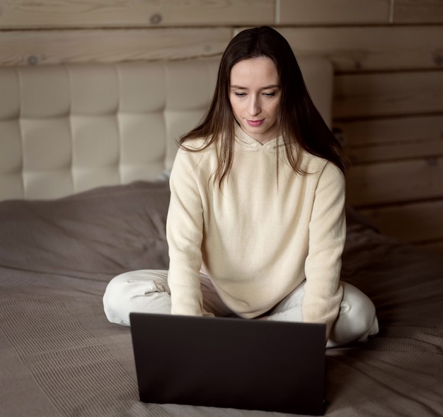 The girl works at the computer from home. A room in a wooden house in beige tones.