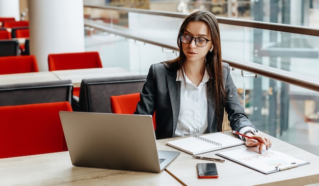 Girl works on a laptop in the workplace. Successful business woman creates a startup and makes decisions.