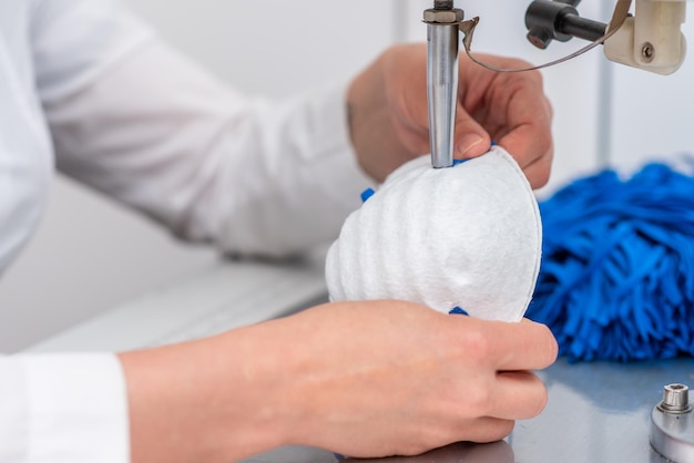 The girl works at the machine for the manufacture of medical masks with nanofibre and solder the loops to them with ultrasound Coronovirus and Covid19 Prevention