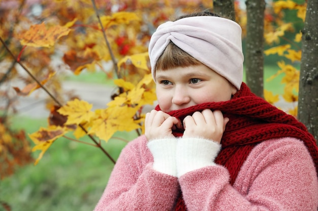 Girl wrap oneself in red scarf to warm in autumn outdoors