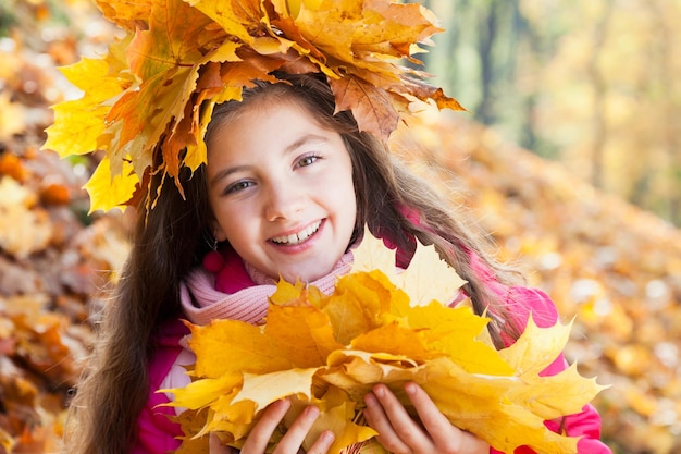 Girl in a wreath of maple leaves with autumn bouquet