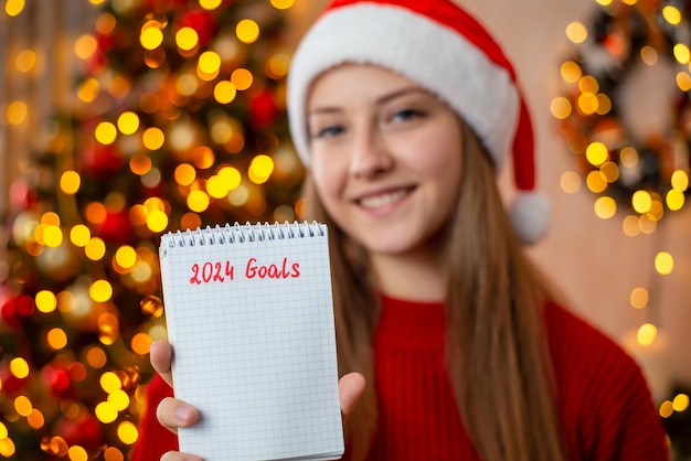 Girl writes goals for 2024 in notebook space for text