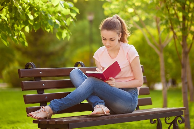 Girl writes in a notebook, sitting on a bench in the Park