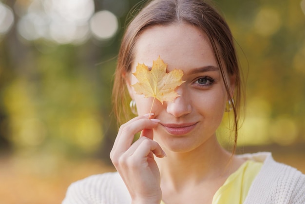 Photo girl in yellow clothes in autumn park rejoices in autumn holding yellow leaves in her hands warm