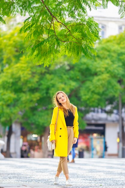 The girl in the yellow coat on the street, stylish outfit, woman