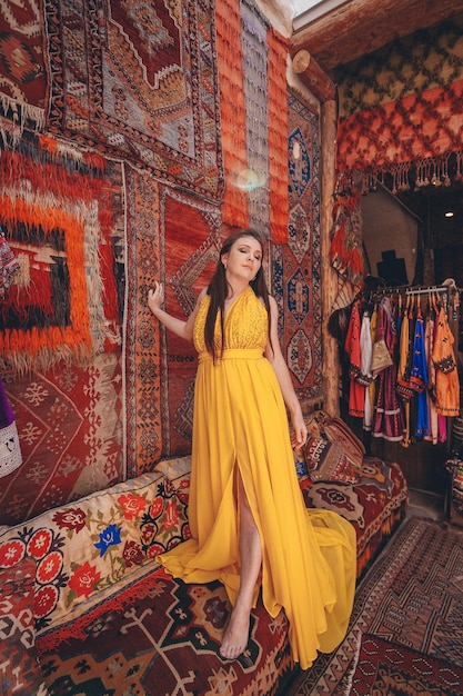 Girl in a yellow flying dress on the floor against the background of carpets Turkish