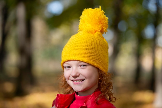 Girl in a yellow knitted hat in autumn Portrait of a child in the autumn park