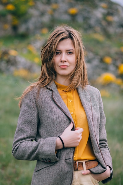 Girl in yellow shirt posing in front of rocks and yellow flowers