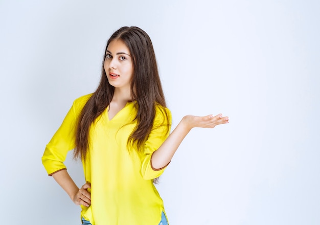 Girl in yellow shirt showing something in her open hand.