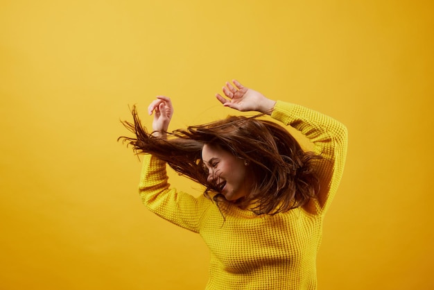 Photo girl in a yellow sweater dancing on a yellow background