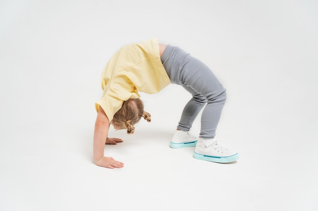 A girl in a yellow tshirt and gray pants a little girl is standing in a bridge an athletic girl on a...