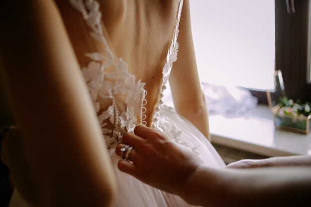 The girlfriend of the bride helps her dress in a white wedding dress in the morning. wedding morning